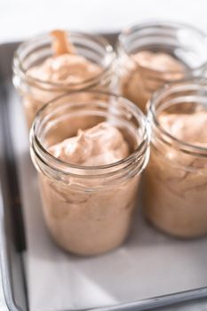 Scooping mixture into the small glass jars to make homemade chocolate ice cream.