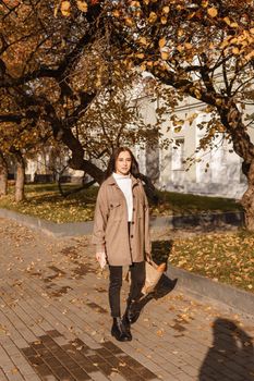 A stylish brunette woman walks around the autumn city. The season is autumn.