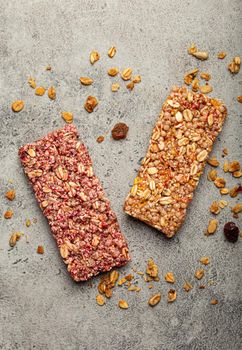 Assorted healthy cereal granola bars with nuts, seeds, fruit and berries on grey stone background, quick and healthy snack or sweet granola breakfast bars rich in energy and fiber .