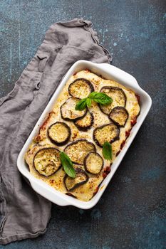 Greek mediterranean dish Moussaka with baked eggplants, ground beef in white ceramic casserole on rustic stone background from above, traditional dish of Greece