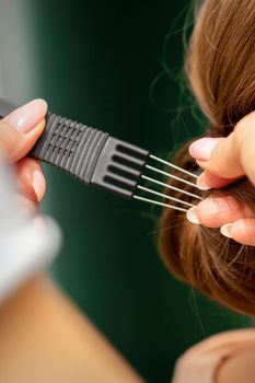 Close Up hairdresser stylist makes hairstyle for a young woman in a beauty salon