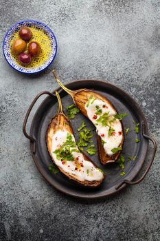 Grilled eggplant served in a pan with yoghurt, fresh cilantro and seasonings. Middle eastern and Mediterranean vegetable meal or appetizer, light and healthy food, top view .