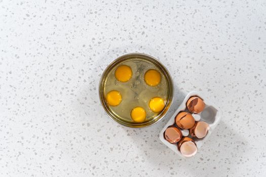 Flat lay. Filling metal pressure cooker insert with raw eggs to cook boiled eggs for potato salad.