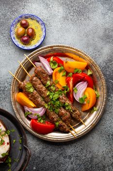 Delicious meat kebab with fresh vegetable salad served on rustic plate, traditional Middle eastern dish. Tasty and healthy meal of Arab or Mediterranean cuisine, from above.