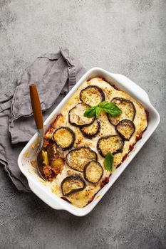 Greek mediterranean dish Moussaka with baked eggplants, ground beef in white ceramic casserole on rustic stone background from above, traditional dish of Greece