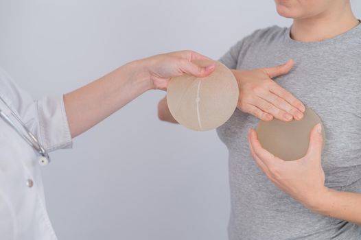 Caucasian woman trying on breast implants. A plastic surgeon helps a patient with a choice