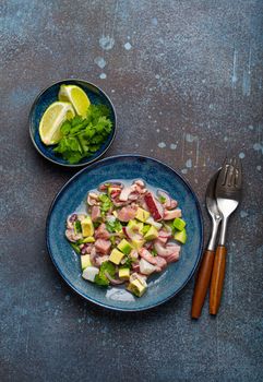 Peruvian ceviche with fresh fish, seafood, avocado on ceramic blue plate on rustic stone background from above, traditional dish of Peru cuisine