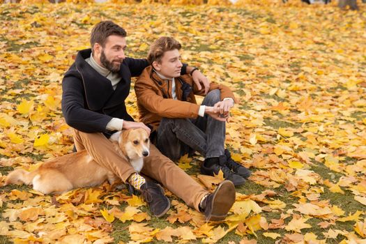 Father and son with a pet on a walk in the autumn park.