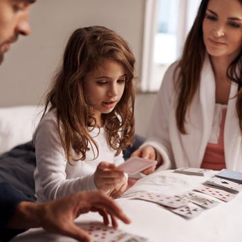 Playing her best cards. a young family playing cards together at home