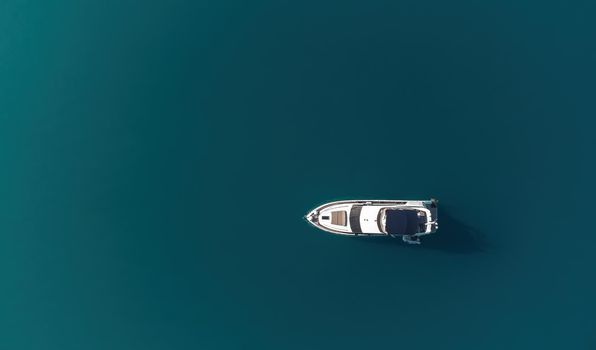 Aerial boat race. Luxury cruise trip. View from above of white boat on deep blue water. Aerial view of rich yacht sailing sea. Motor boat racing wave. Summer journey on luxury ship