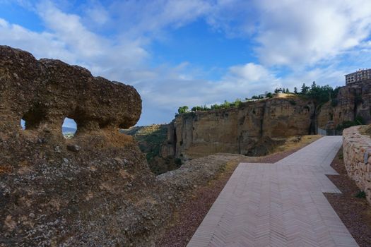 detail of the old wall of ronda with the tajo in the background on a cloudy sky day