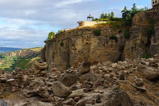 view of the tajo de ronda with strange stones piled up in the foreground sunny day with clouds