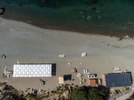 Empty sun loungers under a canopy on the beach. The beach area is empty. No people. White plastic sunbeds under the sun shade. The holiday season ends. Holiday season begins. Waiting for tourists