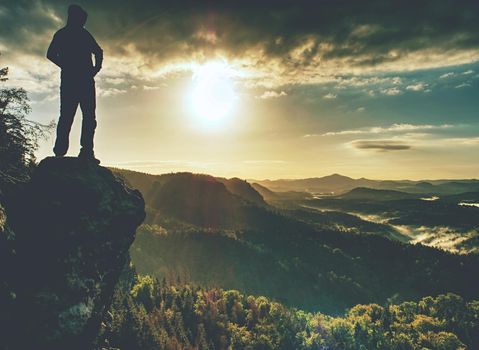 Moment of loneliness. Man on the rock empires and watch over the misty landscape