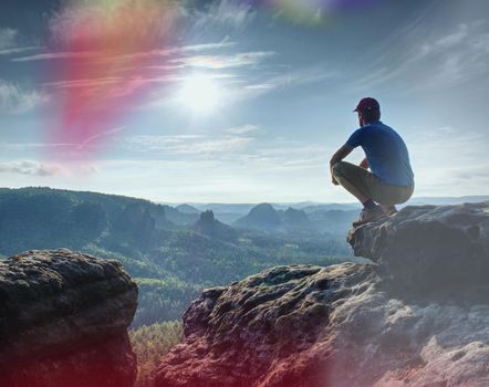 Man sitting on the rock cliff in mountain and watching on sunrise landscape. Nature composition.