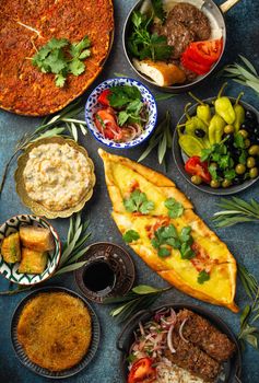 Traditional Turkish food, assorted dishes and mezze appetizers on rustic background from above. Pide, Lahmacun, meat kebab, Turkish meatballs, sweet baklava and Kunefe. Middle East cuisine, top view