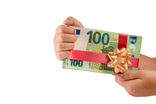 Gift of money, isolate on a white background. The child holds a stack of banknotes in his hands, concept of a gift. Banknotes of 100 euros tied with a red ribbon with a bow