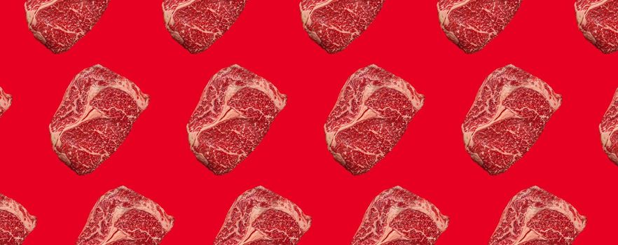 Pattern made of raw meat beef marbled prime cut steak Ribeye on red clean background from above, minimalist beefsteak concept