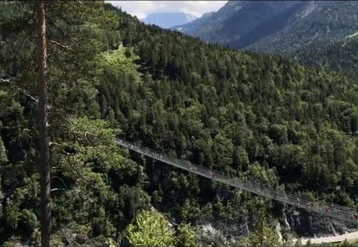 suspension bridge over the gorge slopes of the gorge forests in the background the peaks of the Alps in Austria. High quality photo