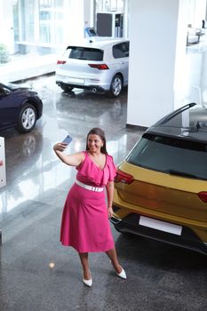 Vertical top view shot of a woman taking selfies with smart phone at car dealership