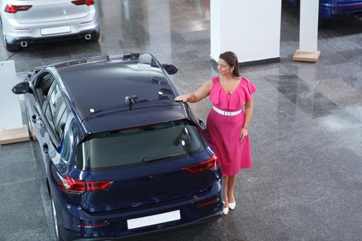 Elegant plus size woman looking at car for sale at dealership