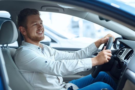 Not leaving without this car! Shot of a happy handsome man smiling joyfully while trying out a new car at the dealership