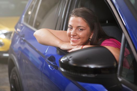Happy woman smiling, sitting in a new auto at car dealership