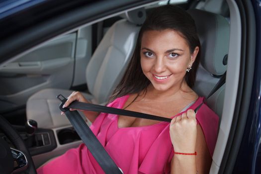 Happy female driver smiling, fastening her seatbelt in a car