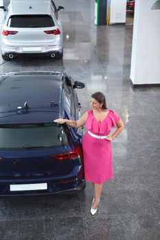 Top view full length shot of a cheerful plus size woman choosing new auto to buy at the dealership