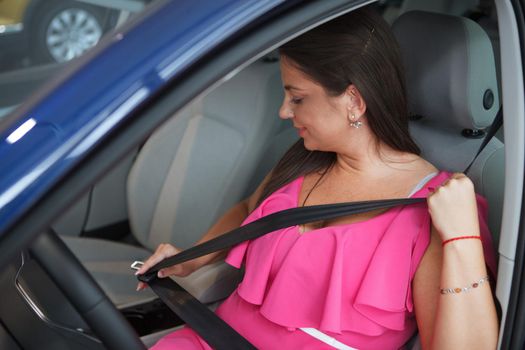 Female driver fastening her seatbelt before driving