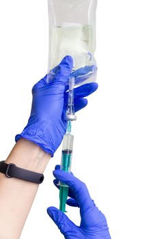 A female doctor or nurse in rubber gloves prepares the injection. Saline solution of sodium chloride. Isotonic solution. Isolated on white.