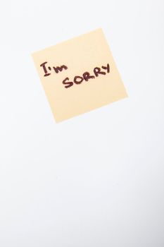 Vertical shot of a handwritten i am sorry note on yellow paper