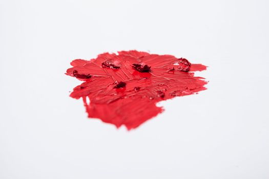 Vibrant red lipstick smudged on white background
