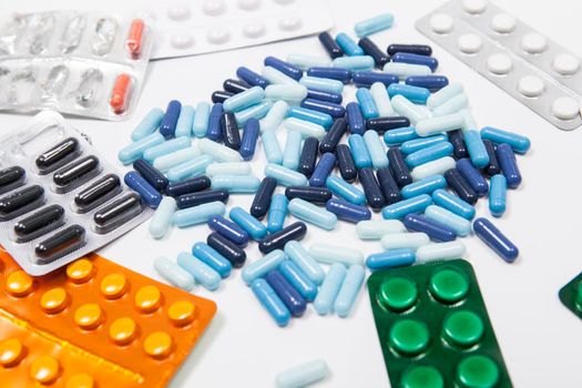 Various pills in blisters and capsules on white background