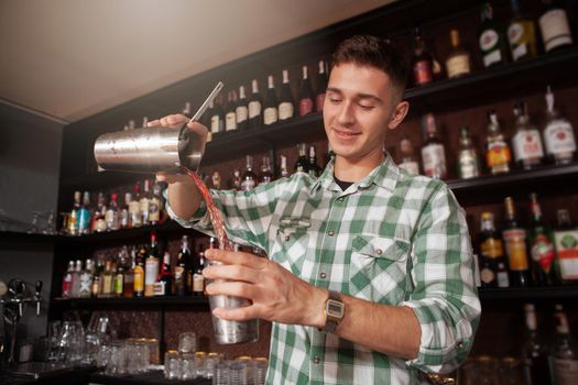 Low angle shot of a handsome cheerful bartender preparing a cocktail, copy space