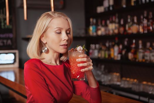Gorgeous woman enjoying delicious cocktail at the bar, copy space