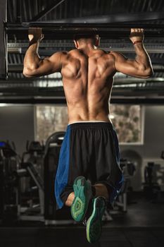 Get fit now. Rearview vertical full length shot of an athletic shirtless man with strong toned body doing pull ups exercising in the gym motivation sports healthcare fitness energy workout concept