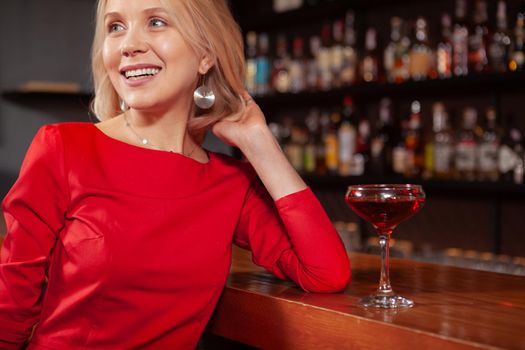 Cropped shot of a charming beautiful woman smiling, looking away, resting at the bar. Attractive woman relaxing at the bar after work