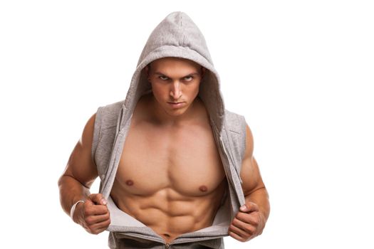 Fierce muscular man opening his hoodie, showing off ripped body, looking to the camera. Young athletic man with sexy muscular torso posing confidently. Handsome strong bodybuilder flexing his abs
