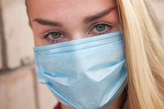 Cropped close up of the face of a woman wearing protective medical mask during pandemic