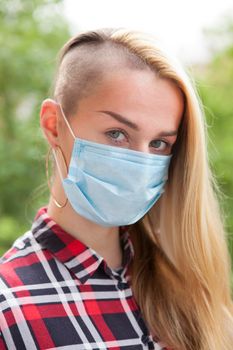 Vertical close up of a woman with medical mask on her face looking to the camera