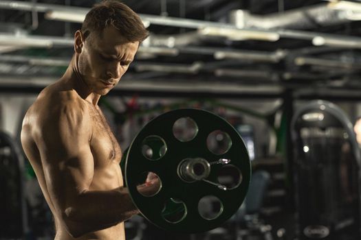 Training routine. Profile shot of a handsome shirtless muscular man with sexy fit and toned body doing biceps exercise using barbell at the gym copyspace fitness lifestyle masculinity activity concept