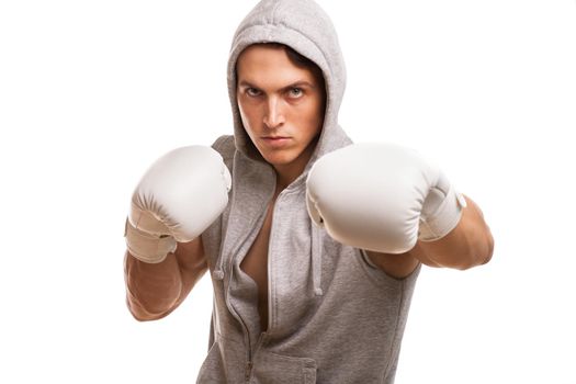 Young handsome muay thai boxer looking confidently to the camera while shadow boxing. Professional mma figter training isolated, copy space. Athletic man in boxing gloves. Achievement, sports concept