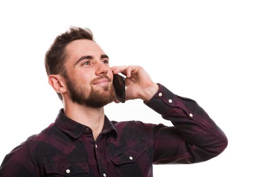 Close up portrait of a handsome bearded man talking on the phone, looking away happily, isolated. Attractive man smiling, calling using his smart phone, copy space. Technology, communication concept