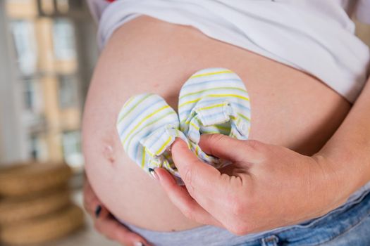 Belly of pregnant woman. A pregnant woman cannot close her jeans. The concept of clothing becomes small due to the growth of the abdomen