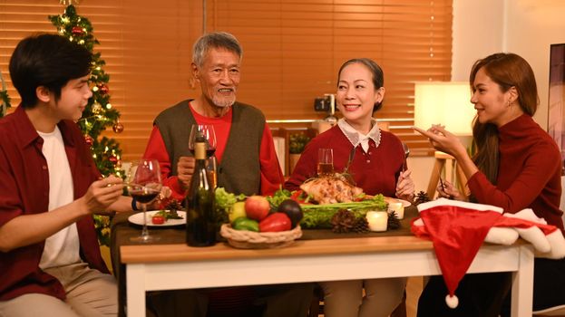 Joyful family talking and celebrating Christmas at dining table. Holidays and celebration concept.