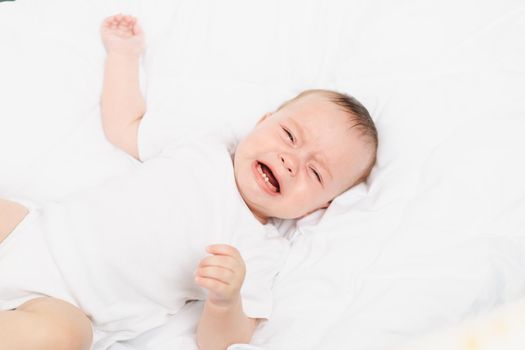 The baby is crying in his crib . The baby 's teeth are teething . Colic in babies . Hungry baby . Baby on a white background