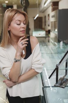 Vertical shot of a gorgeous woman trying on jewelry at the store