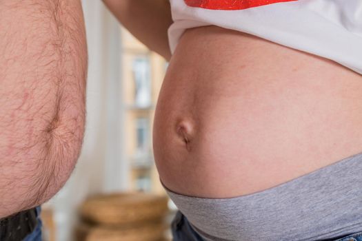 Belly of pregnant woman. A pregnant woman cannot close her jeans. The concept of clothing becomes small due to the growth of the abdomen