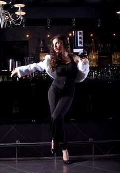 Beauty woman stand near bar in luxury cloth and white fur coat
